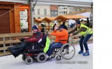3 personen op de schaatsbaan waarbij 1 elektrische en 1 manuele rolstoel