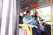 2 mensen in een lijnbus kijkend op gsm